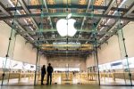 Modern Apple Store with large glass entrance and illuminated Apple logo, showcasing minimalist interior design and customers browsing technology products.