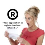 A woman with a shock looked on her face a she reads a rejection of her USPTO trademark application