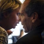 Businesswoman whispering to her colleague around a conference table Protecting Trade Secret - Confidentiality Agreement