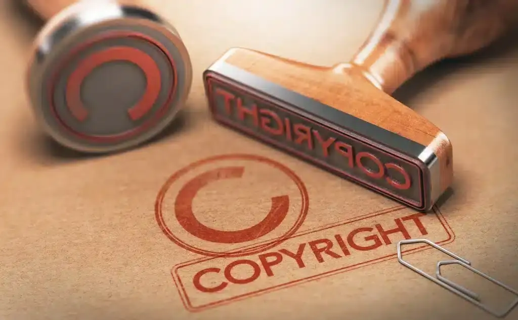 Close-up of a wooden copyright stamp imprinting the copyright symbol and word on brown paper, symbolizing intellectual property protection and legal rights.